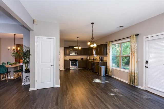 a open kitchen with stainless steel appliances granite countertop a stove top oven a refrigerator a dining table and chairs with wooden floor