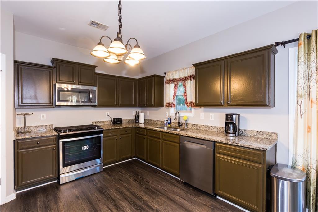 4245 Pear Haven Lane Gainesville, GA 30504 - Photo 13 of 39 a kitchen with stainless steel appliances granite countertop a sink a stove a microwave and wooden floors