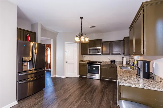 a kitchen with granite countertop a refrigerator oven a sink dishwasher and wooden floor