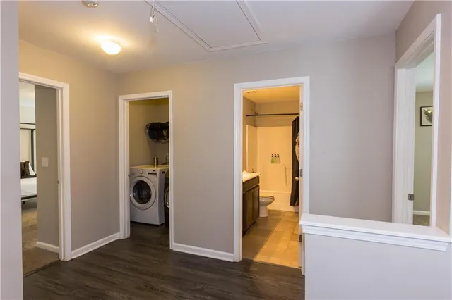 a view of a hallway with wooden floor a sink and a bathroom