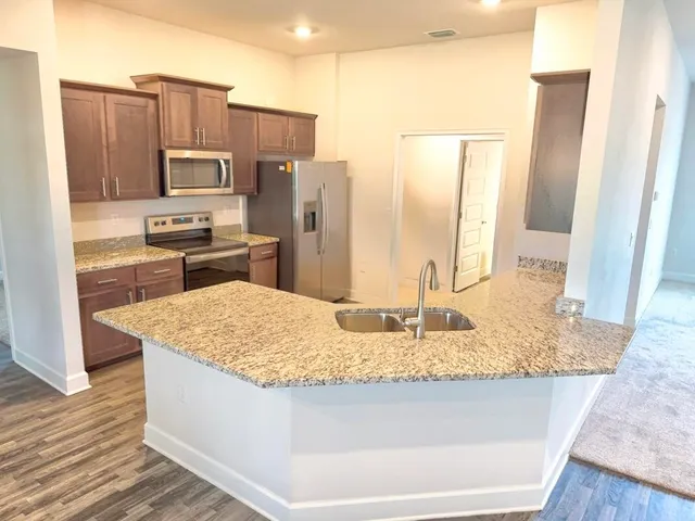 a kitchen with kitchen island granite countertop a sink stove and refrigerator