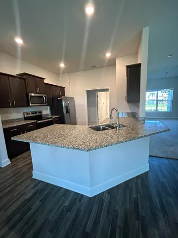 a kitchen with kitchen island granite countertop a stove a sink and a microwave