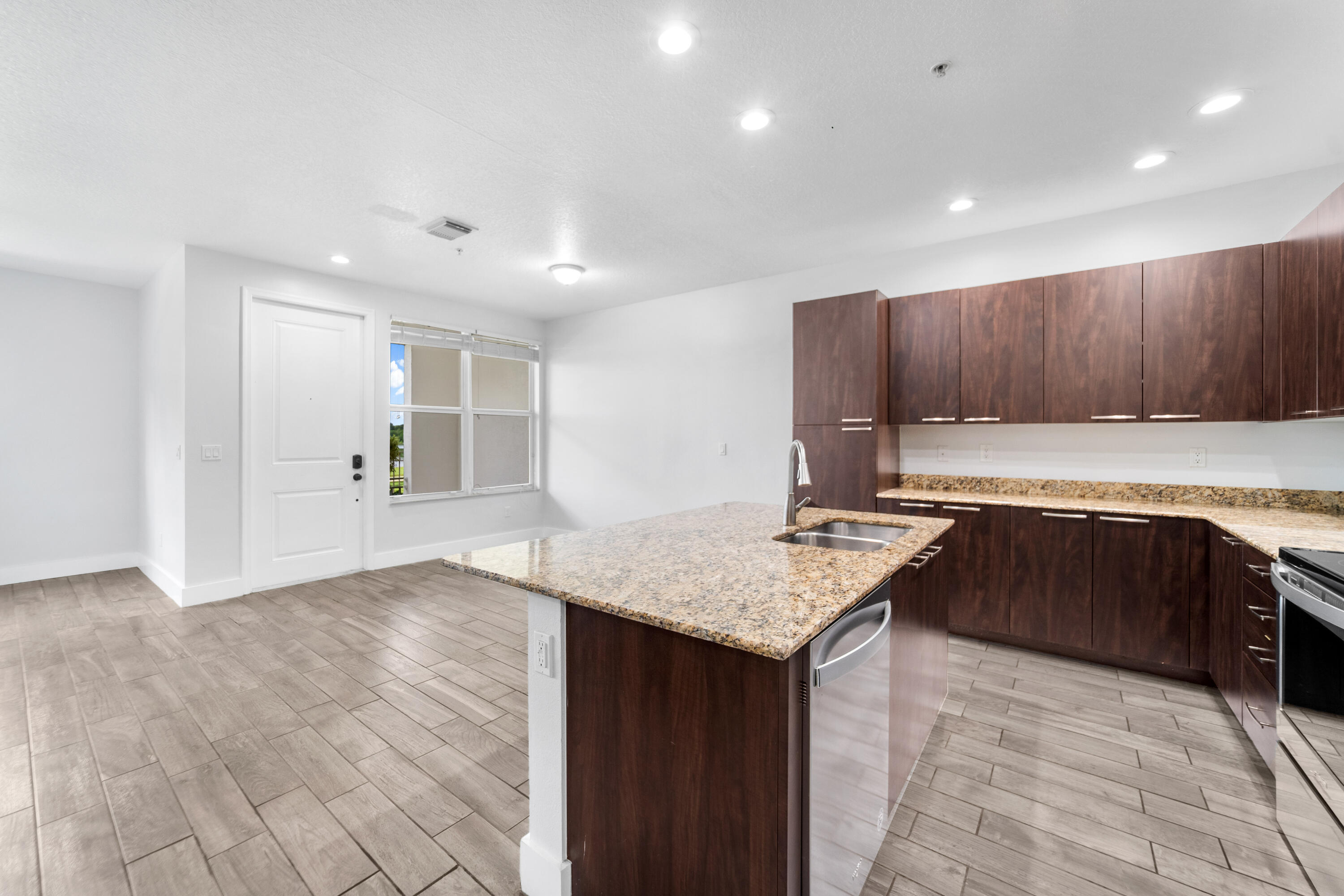 1430 Northwest 48th Lane Boca Raton, FL 33431 - Photo 8 of 54 a kitchen with kitchen island granite countertop a stove top oven a sink and dishwasher with wooden cabinets