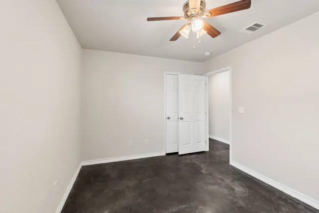 an empty room with a window and a fan
