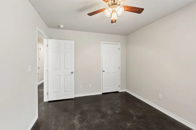 an empty room with a ceiling fan and carpet