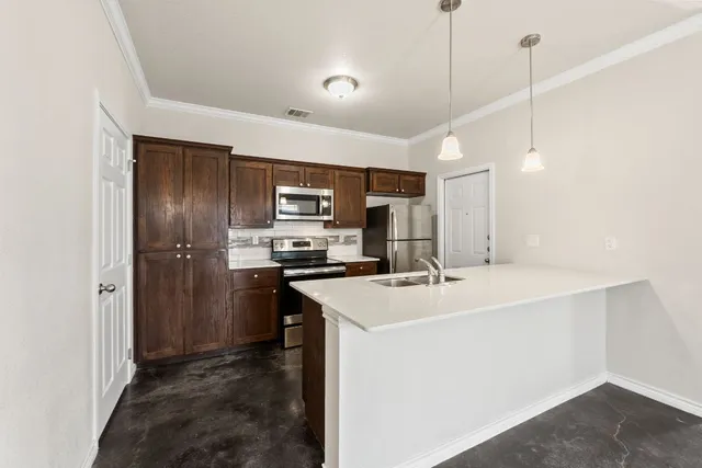a view of a kitchen with a sink and dishwasher a stove top oven with wooden floor