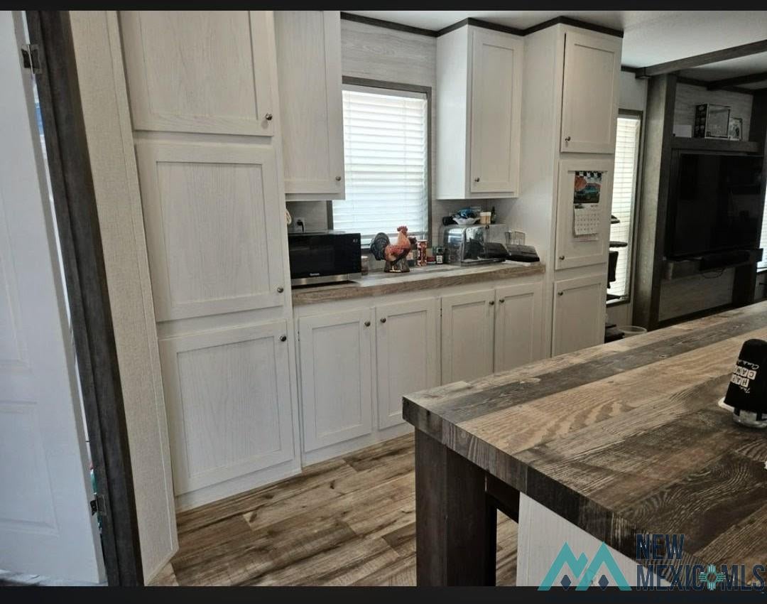 14006 Ciguena Road Southwest Deming, NM 88030 - Photo 2 of 49 Kitchen featuring white cabinetry with dark hardware, laminate countertops, and wood-finish flooring
