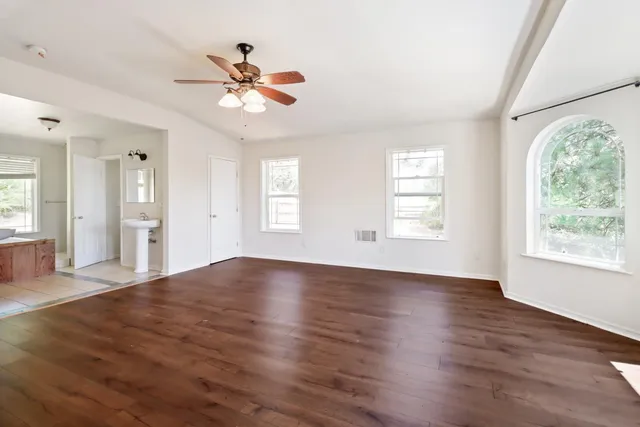 a view of an empty room with wooden floor and a window