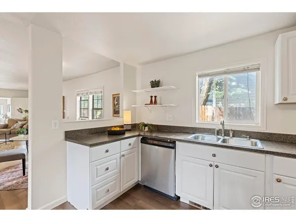 a kitchen with granite countertop a sink white cabinets and a window