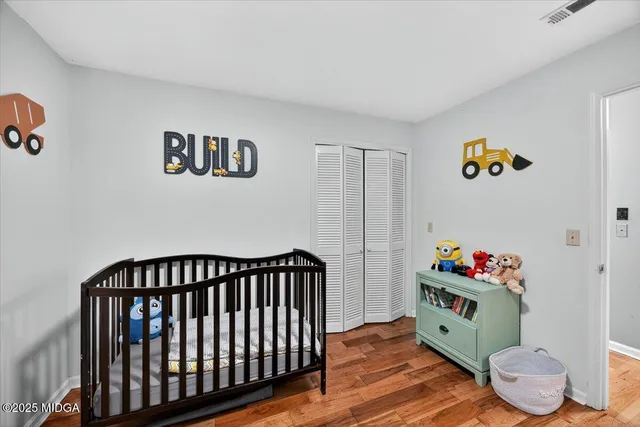 a living room with baby crib and wooden floor