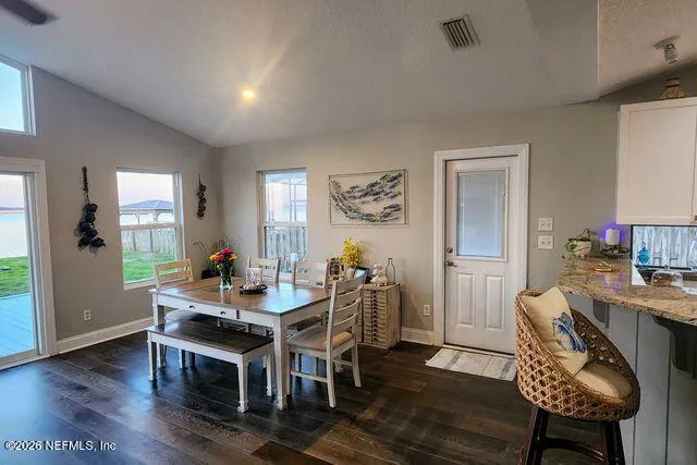 a kitchen with stainless steel appliances granite countertop a table chairs sink and cabinets