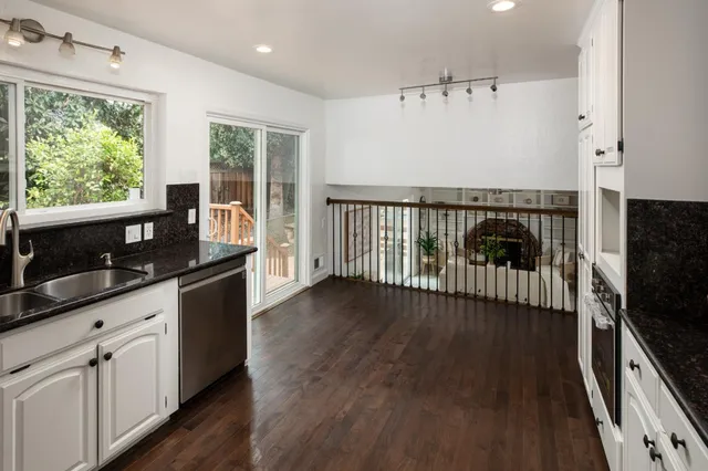 a kitchen with granite countertop a stove a sink and a wooden floors