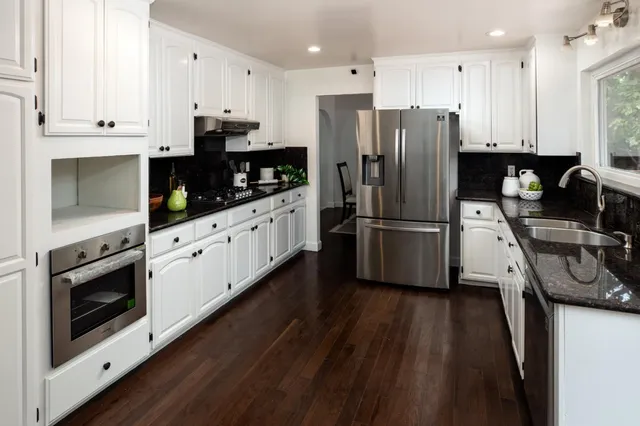 a kitchen with granite countertop a refrigerator oven a stove top oven and a counter space