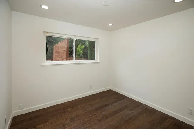 an empty room with wooden floor and a window