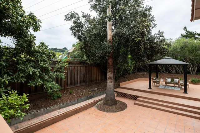 a view of backyard with wooden fence and trees