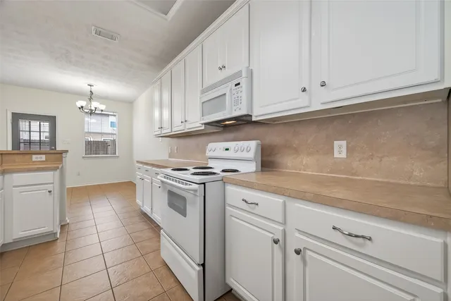 a kitchen with granite countertop white cabinets and white appliances