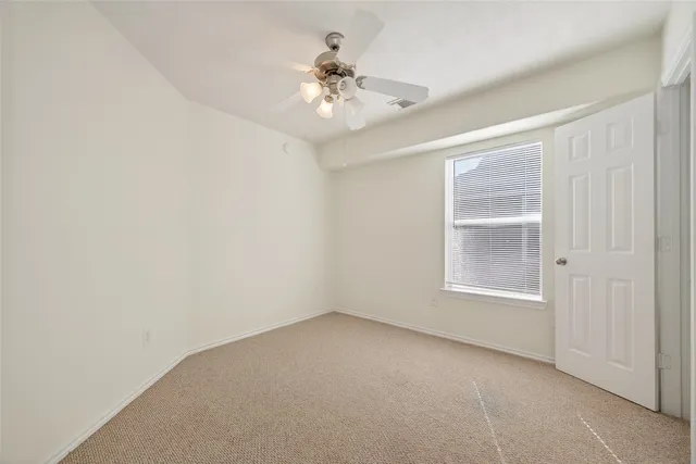 an empty room with chandelier fan and windows