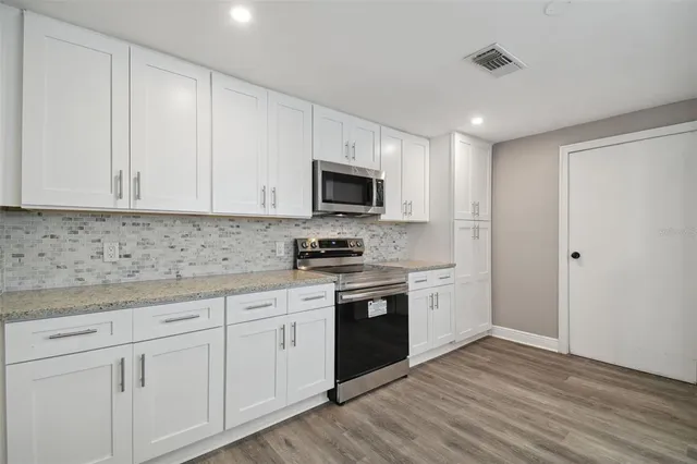 a kitchen with cabinets stainless steel appliances and wooden floor