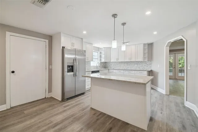 a large kitchen with granite countertop a large counter top stainless steel appliances and cabinets