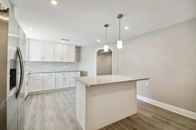 a open kitchen with a sink a refrigerator and wooden floor