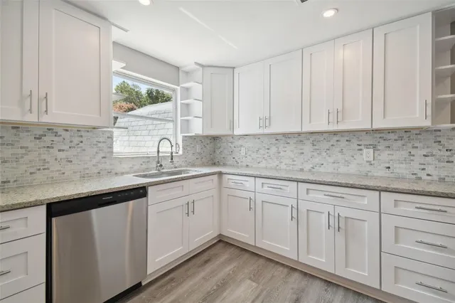 a kitchen with white cabinets sink and dishwasher