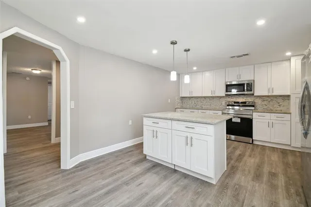 a kitchen with granite countertop white cabinets and stainless steel appliances