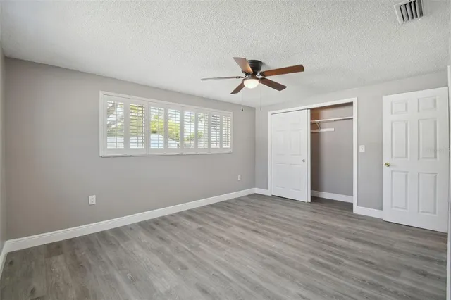 a view of empty room with wooden floor and fan