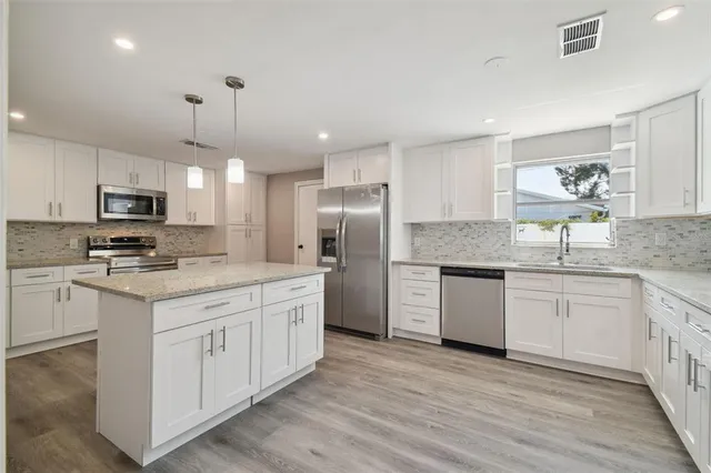a kitchen with granite countertop white cabinets and refrigerator