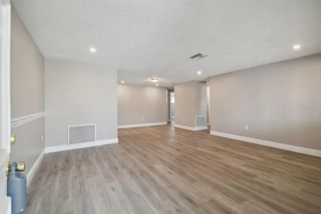 a view of an empty room with wooden floor