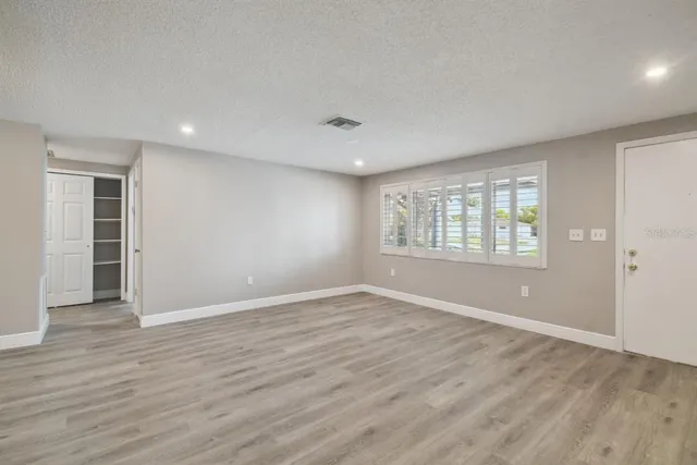 an empty room with wooden floor and windows