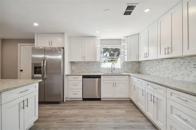 a kitchen with white cabinets appliances and sink