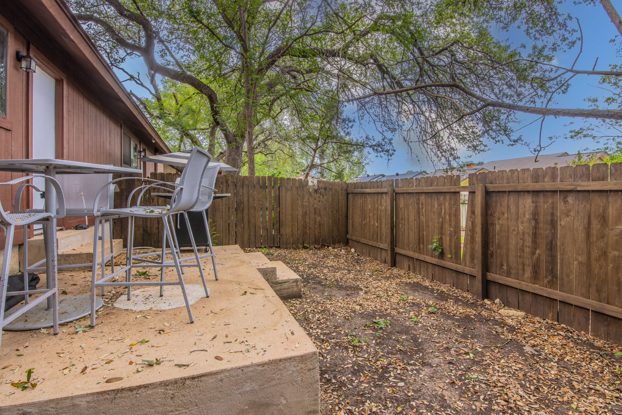 1008 Milford Way Austin, TX 78745 - Photo 39 of 40 Private outdoor patio featuring a wooden privacy fence, mature trees, and a concrete patio slab