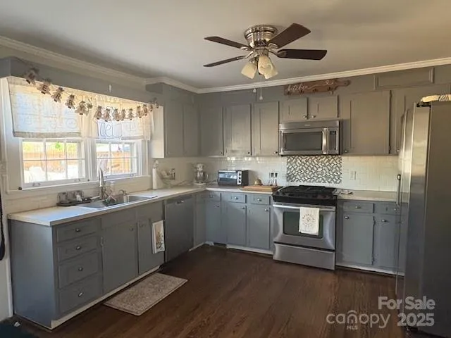 a kitchen with a sink appliances cabinets and a large window