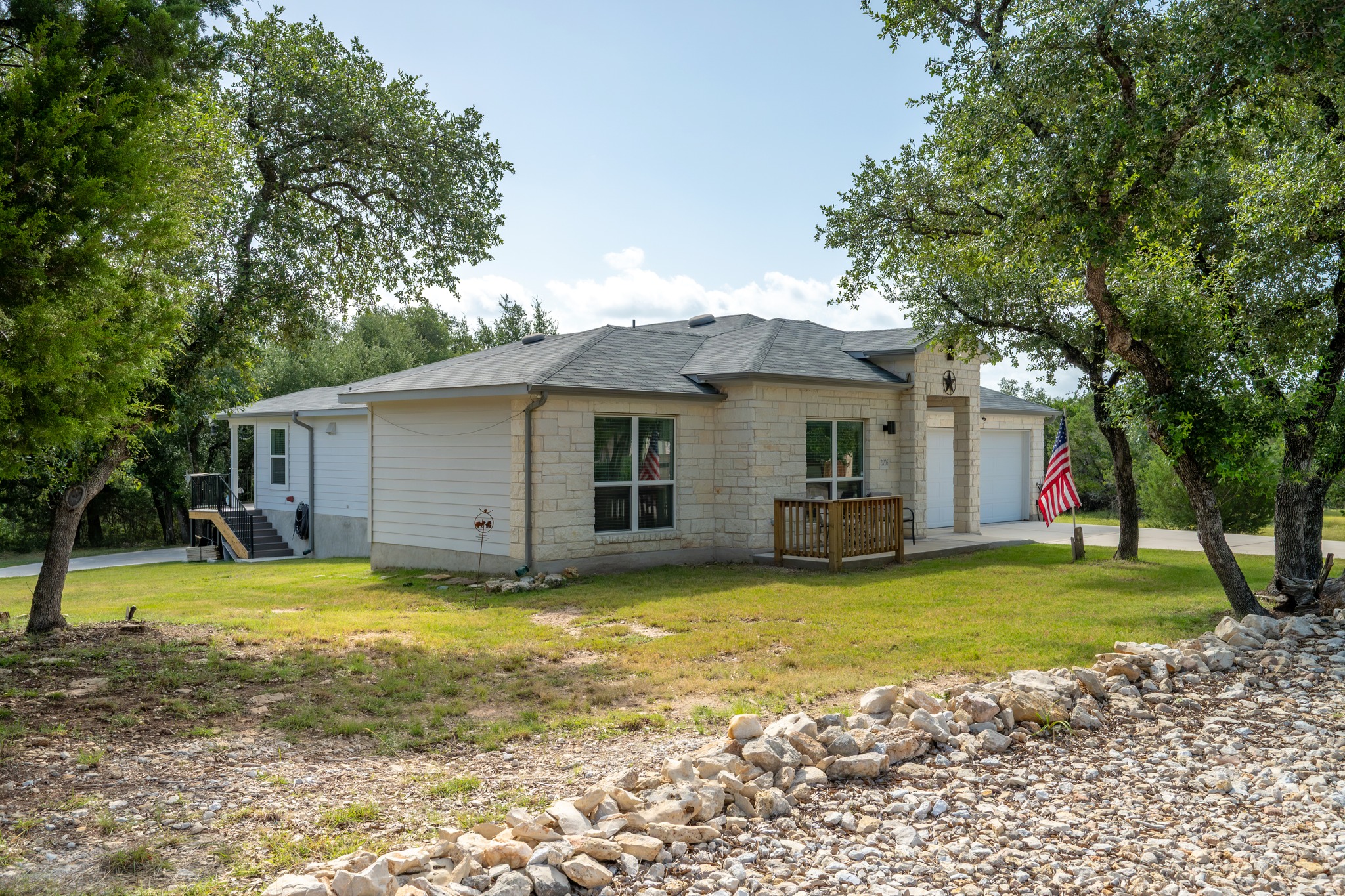 21006 Santa Rosa Avenue Lago Vista, TX 78645 - Photo 2 of 26 A welcoming stone and siding facade is nestled among mature trees on a spacious, well-maintained lot.