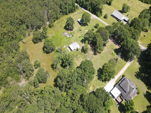an aerial view of residential house with outdoor space and trees all around