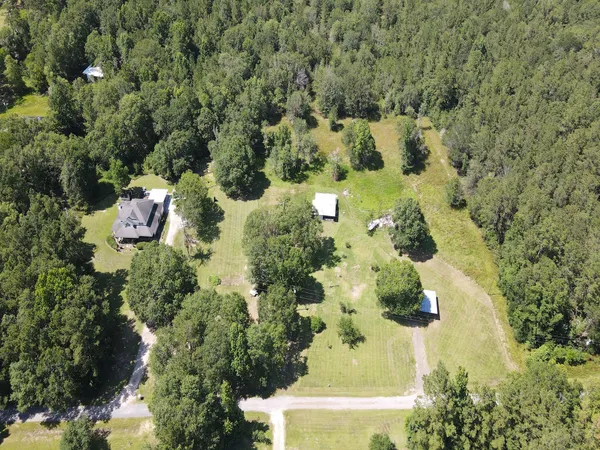 an aerial view of residential house with outdoor space and trees all around