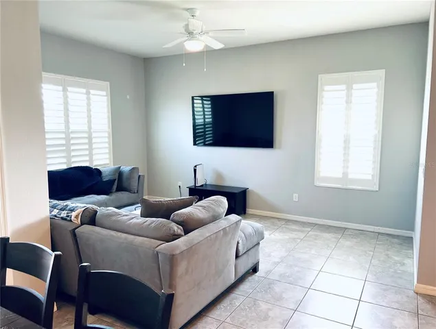 a living room with furniture a flat screen tv and a window