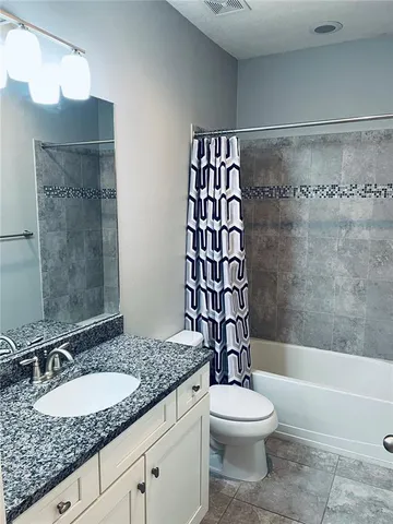 a bathroom with a granite countertop bathtub sink vanity mirror and toilet