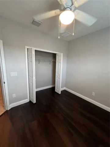 an empty room with wooden floor closet and windows