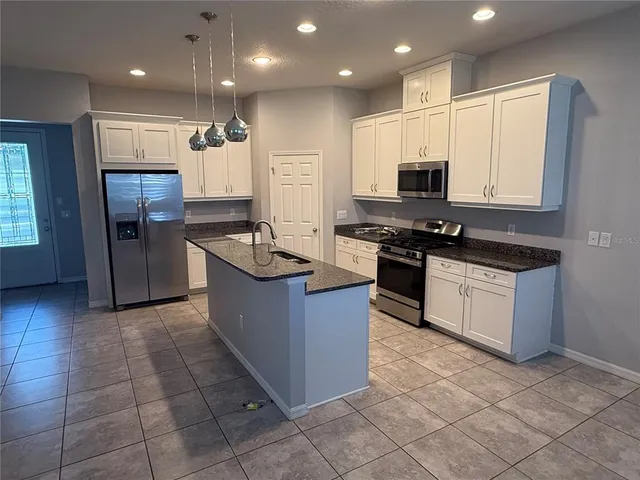 a large kitchen with stainless steel appliances granite countertop a stove a sink and a refrigerator
