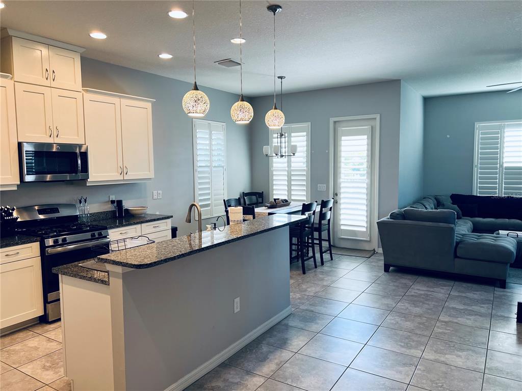 11124 Great Neck Road Riverview, FL 33578 - Photo 7 of 26 a kitchen with stainless steel appliances granite countertop a sink a stove a dining table and chairs