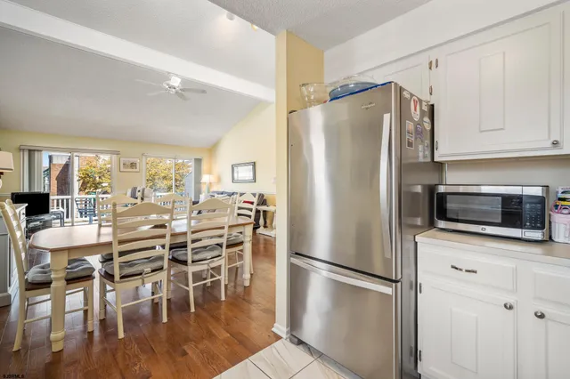 a kitchen with stainless steel appliances a refrigerator a stove a dining table and chairs with wooden floor