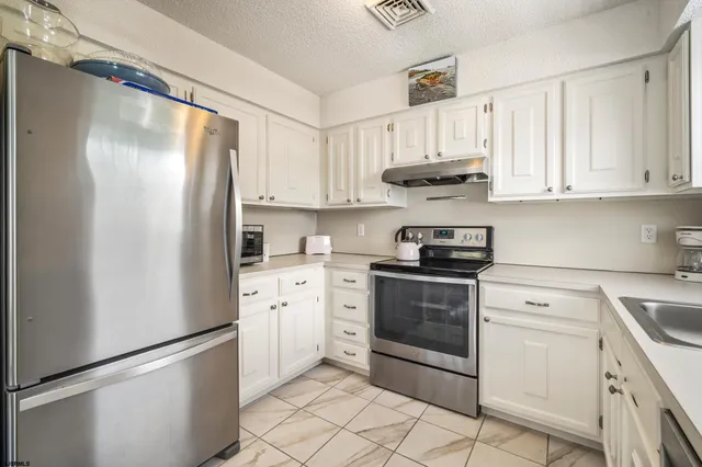 a kitchen with stainless steel appliances white cabinets and a refrigerator