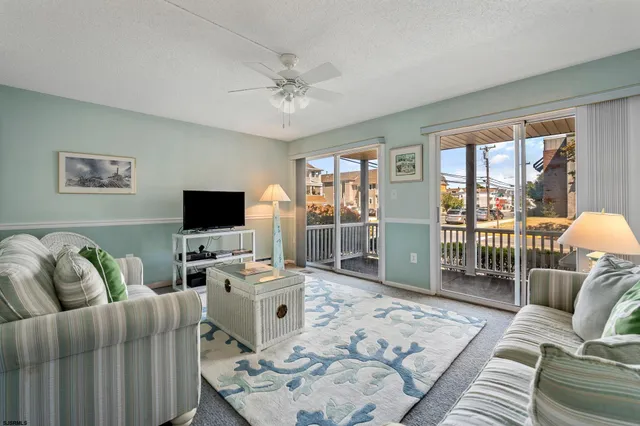 a living room with furniture a flat screen tv and a floor to ceiling window