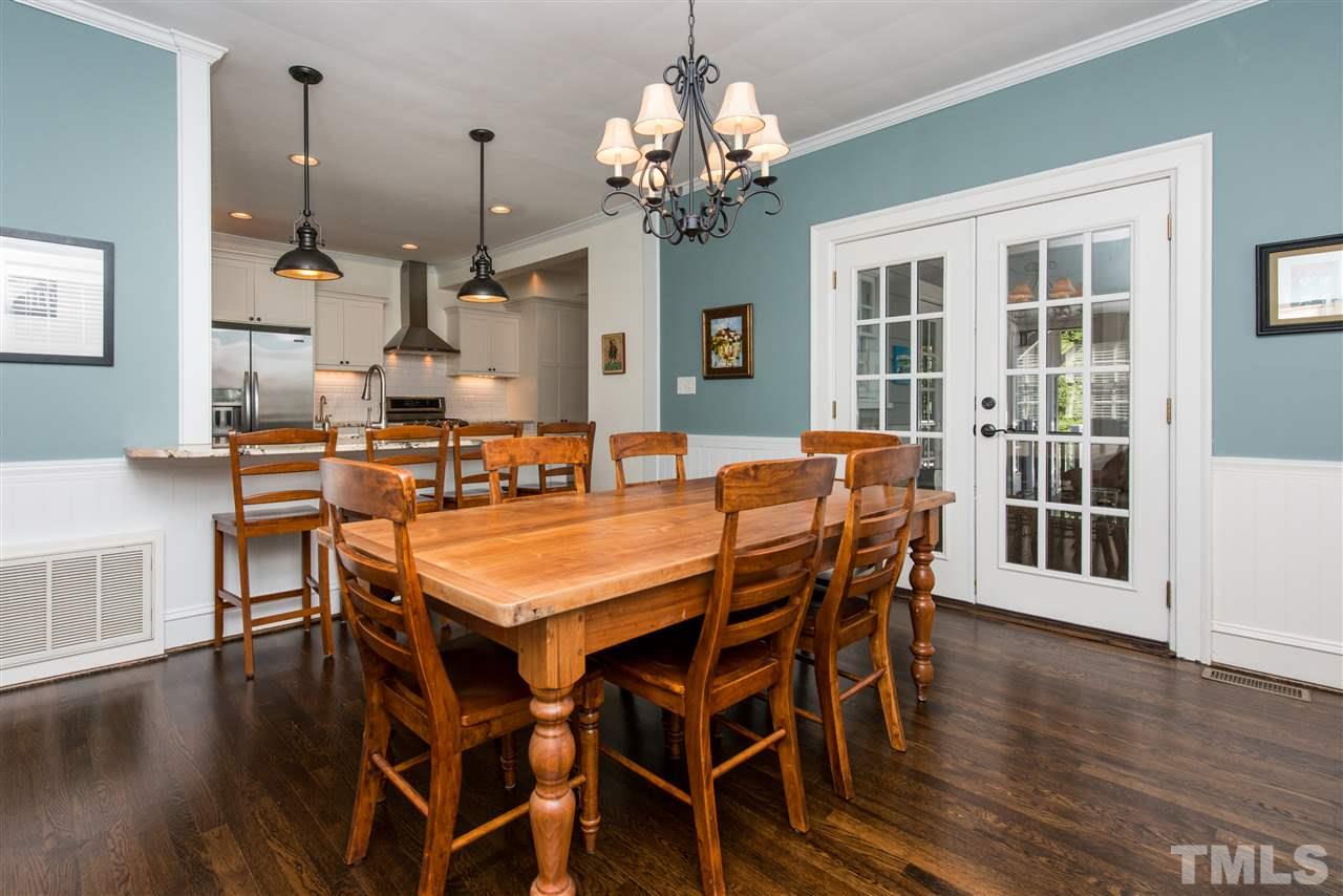 2218 Creston Road Raleigh, NC 27608 - Photo 6 of 25 a dining room with wooden floor a chandelier a wooden table and chairs