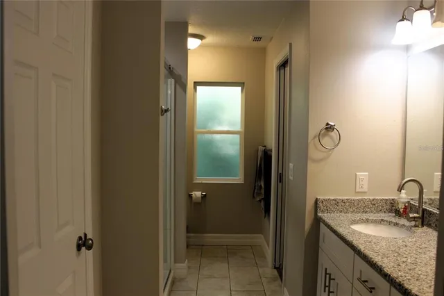 a bathroom with a granite countertop sink a mirror and shower