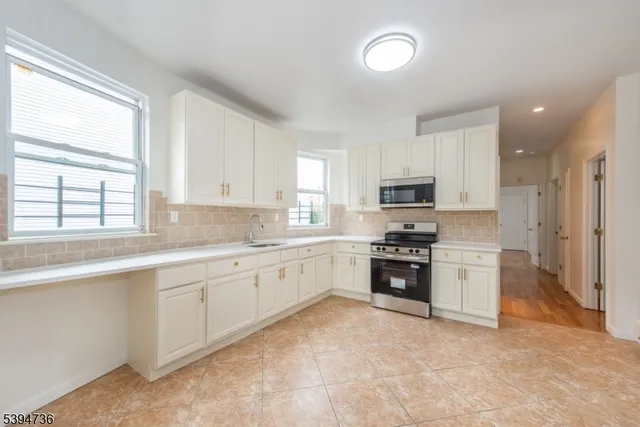 a large kitchen with stainless steel appliances granite countertop a stove top oven a sink and dishwasher