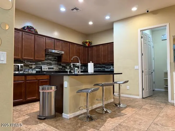 a kitchen with stainless steel appliances a dining table chairs and refrigerator