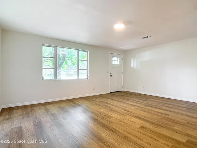 an empty room with wooden floor and windows