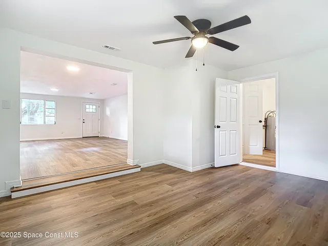 a view of a livingroom with wooden floor and a ceiling fan